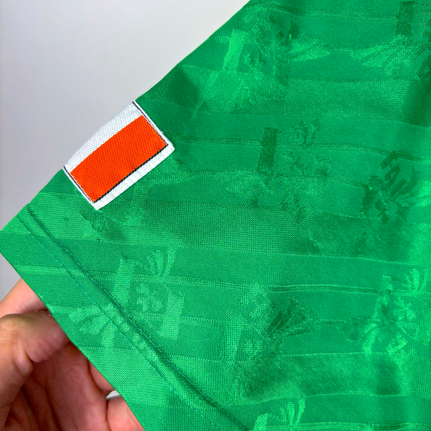 Green vintage football shirt sleeve with orange, white, and green Ireland flag patch, retro football shirts texture. - Eire Ireland 1994-1995 USA World Cup Home Football Shirt Adidas