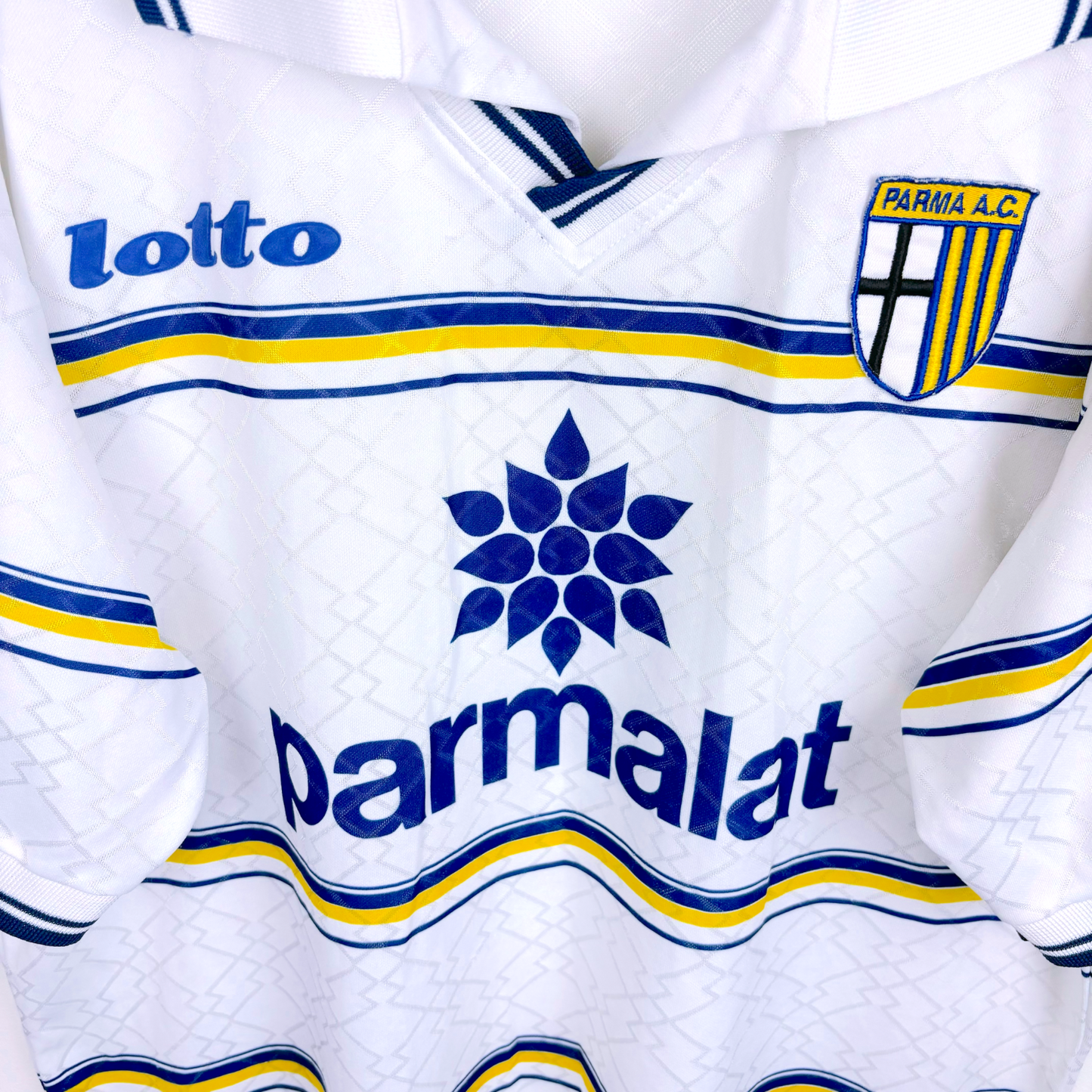 Close up of a Parma vintage soccer jersey produced by Lotto. Embroidered Parma badge with iconic Parmalat sponsor.