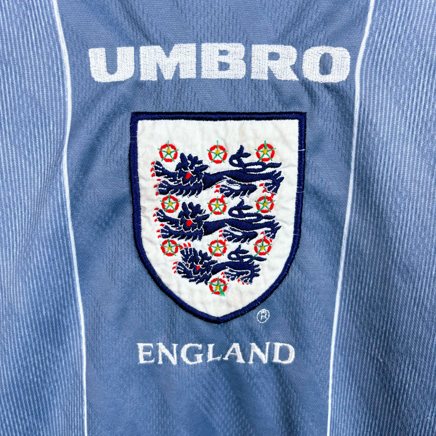 Close up view of fully embroidered Three Lions crest and Umbro writing on an England retro football shirt produced by Umbro.