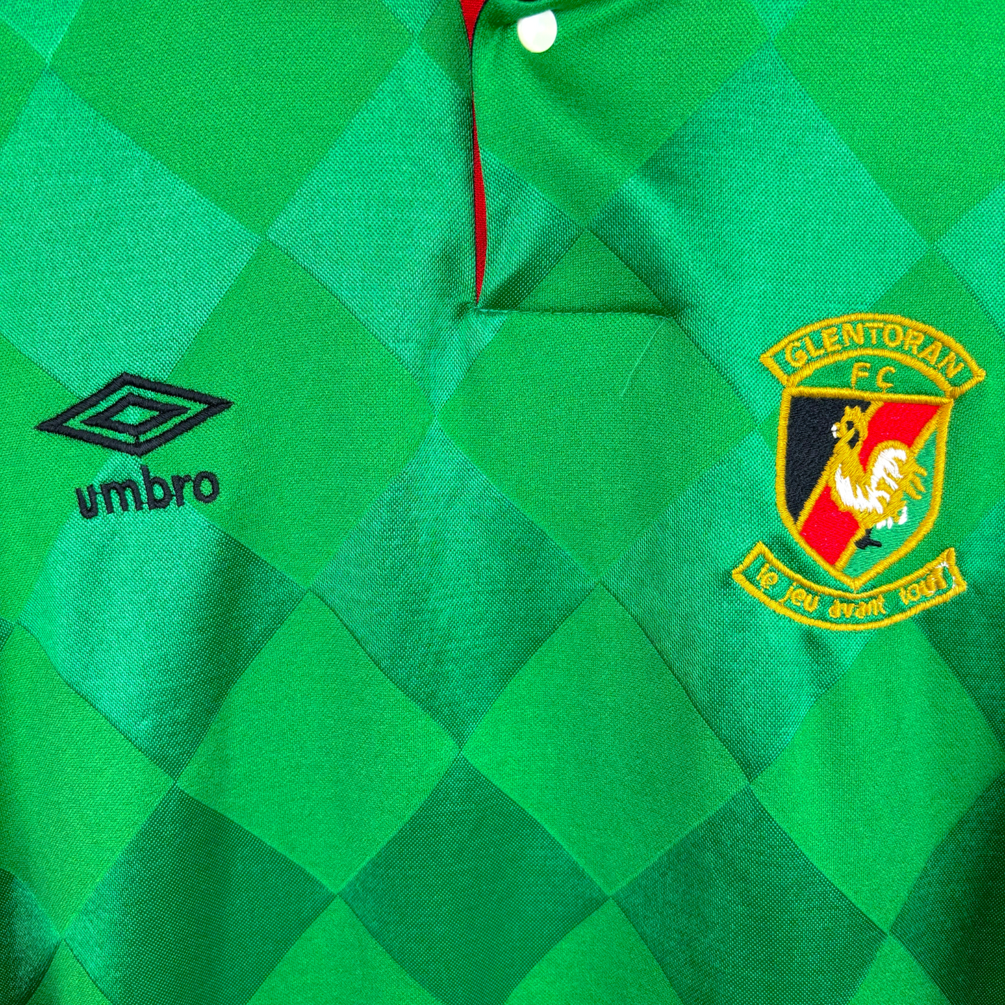 Central close up view of old Glentoran football jersey produced by Umbro. Green jacquard body featuring embroidered Umbro logo and club crest