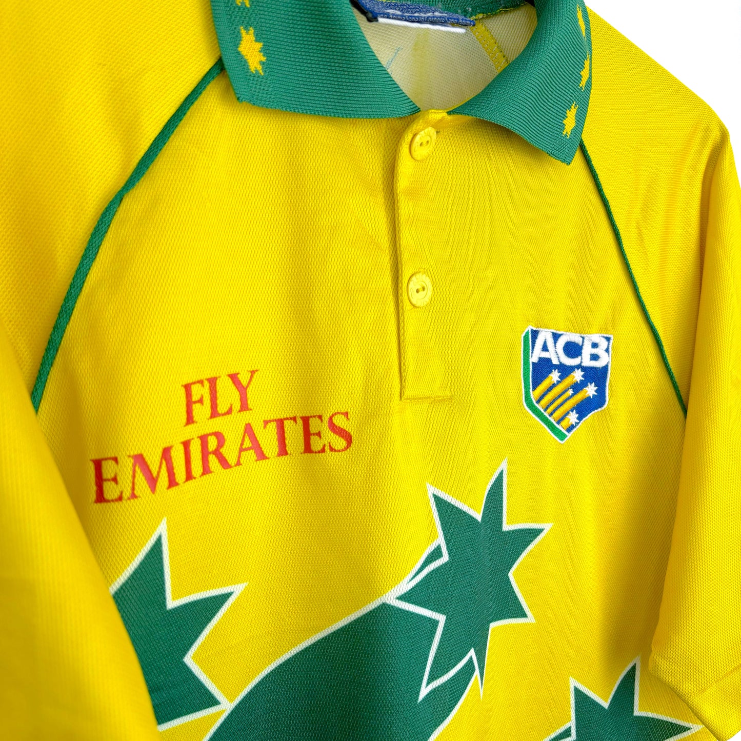 Classic Australia 1999 World Cup cricket shirt by Asics, close-up side view of Fly Emirates sponsor logo and yellow and green fabric details