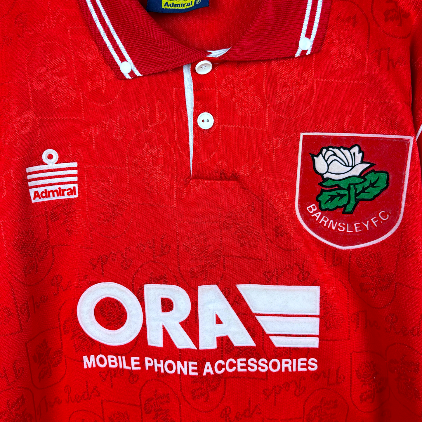 Barnsley 1996-1997 home classic football shirt produced by Admiral. Close up of ORA sponsor and Admiral logo as well as club badge.