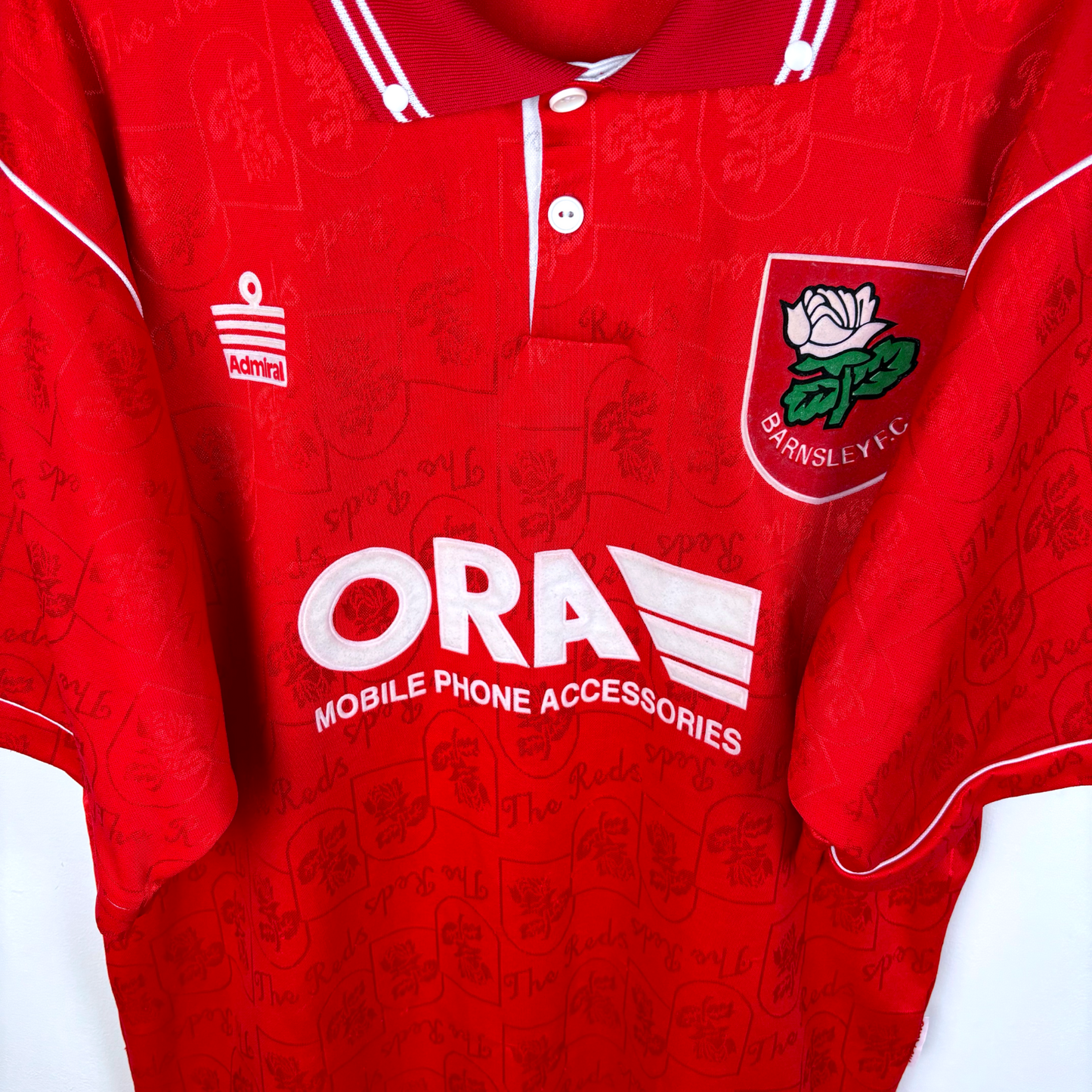 Barnsley 1996-1997 home vintage football shirt made by Admiral. Downward view of of ORA sponsor and Admiral logo as well as club badge.