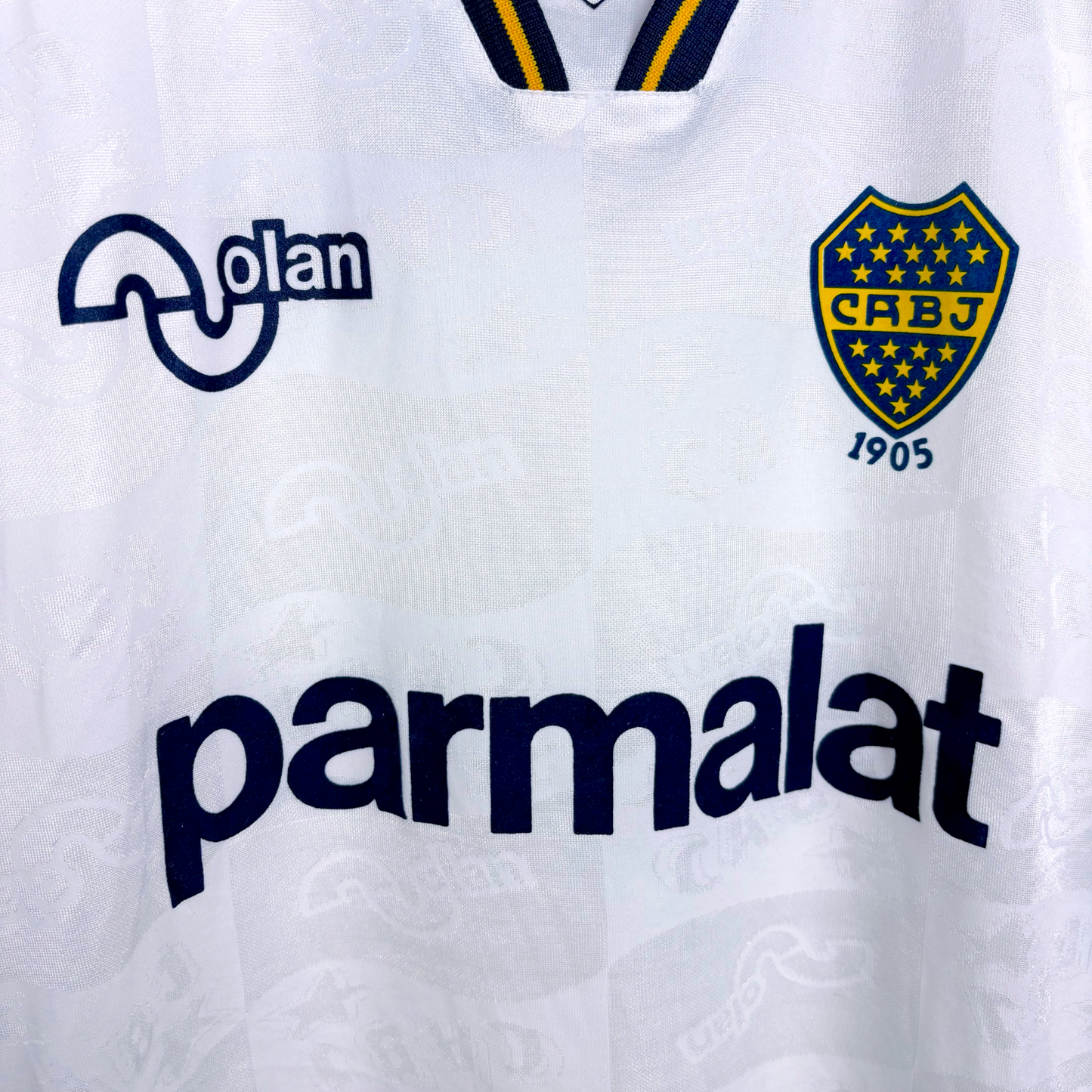 Boca Juniors 1995-1996 away classic football shirt produced by OLAN. Close up of Boca crest and OLAN and Parmalat sponsors in navy.