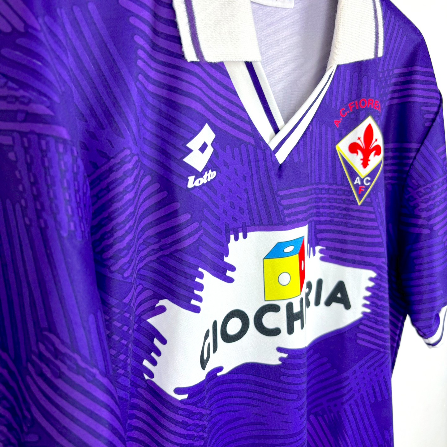 Side view of Fiorentina 1991-1992 home retro football shirt made by Lotto. Purple body spanned by Lotto logo pattern and white collar.