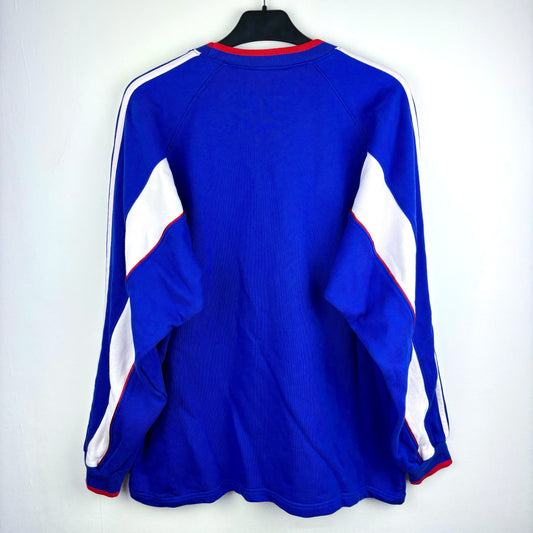 Rear view of Japan 1999-2000 adidas vintage football sweatshirt. Blue body with white vertical swooshes and red trim. Brand new with tags attached.