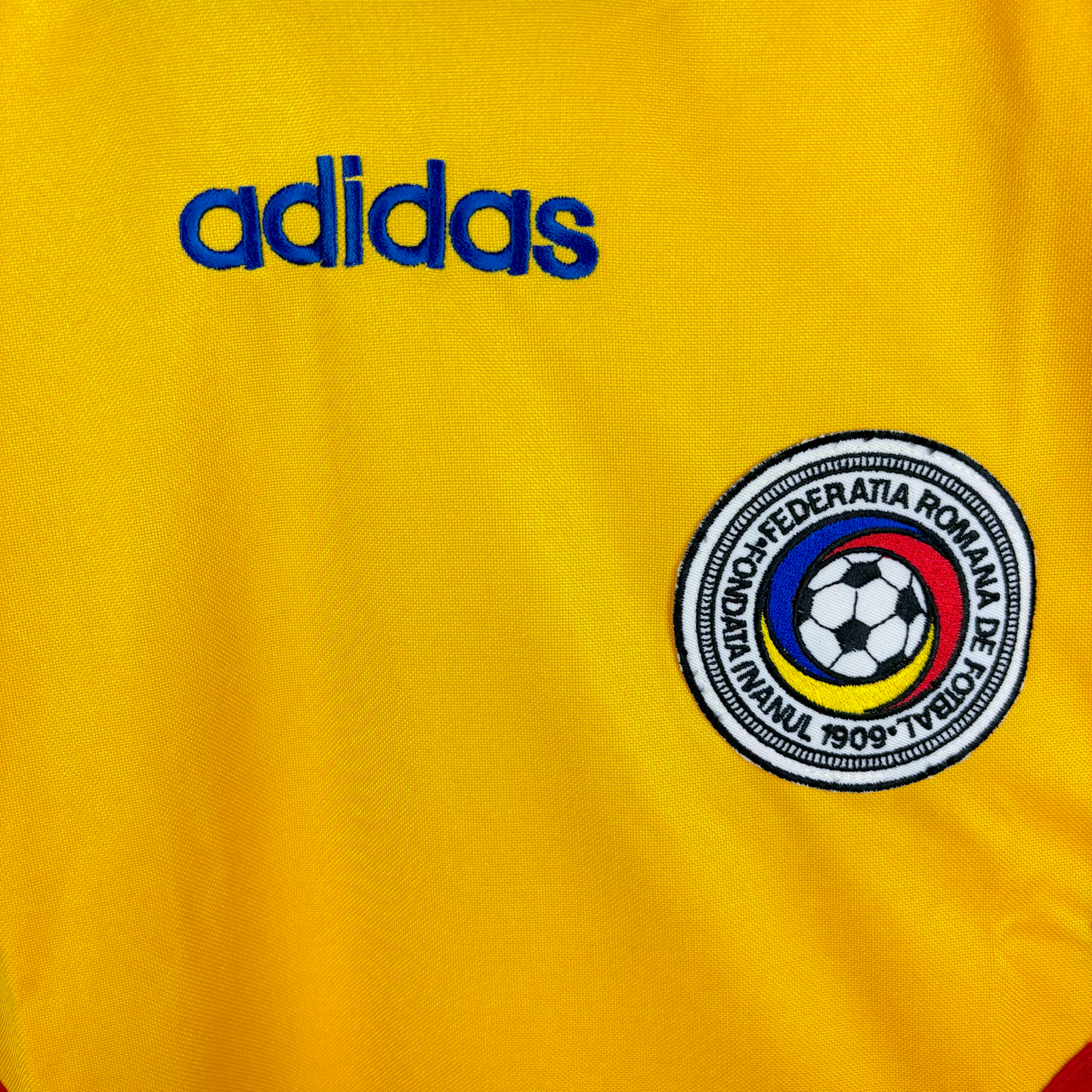 Romania 1994-1995 classic football shirt produced by Adidas. Close up of national team crest and adidas text embroidery.