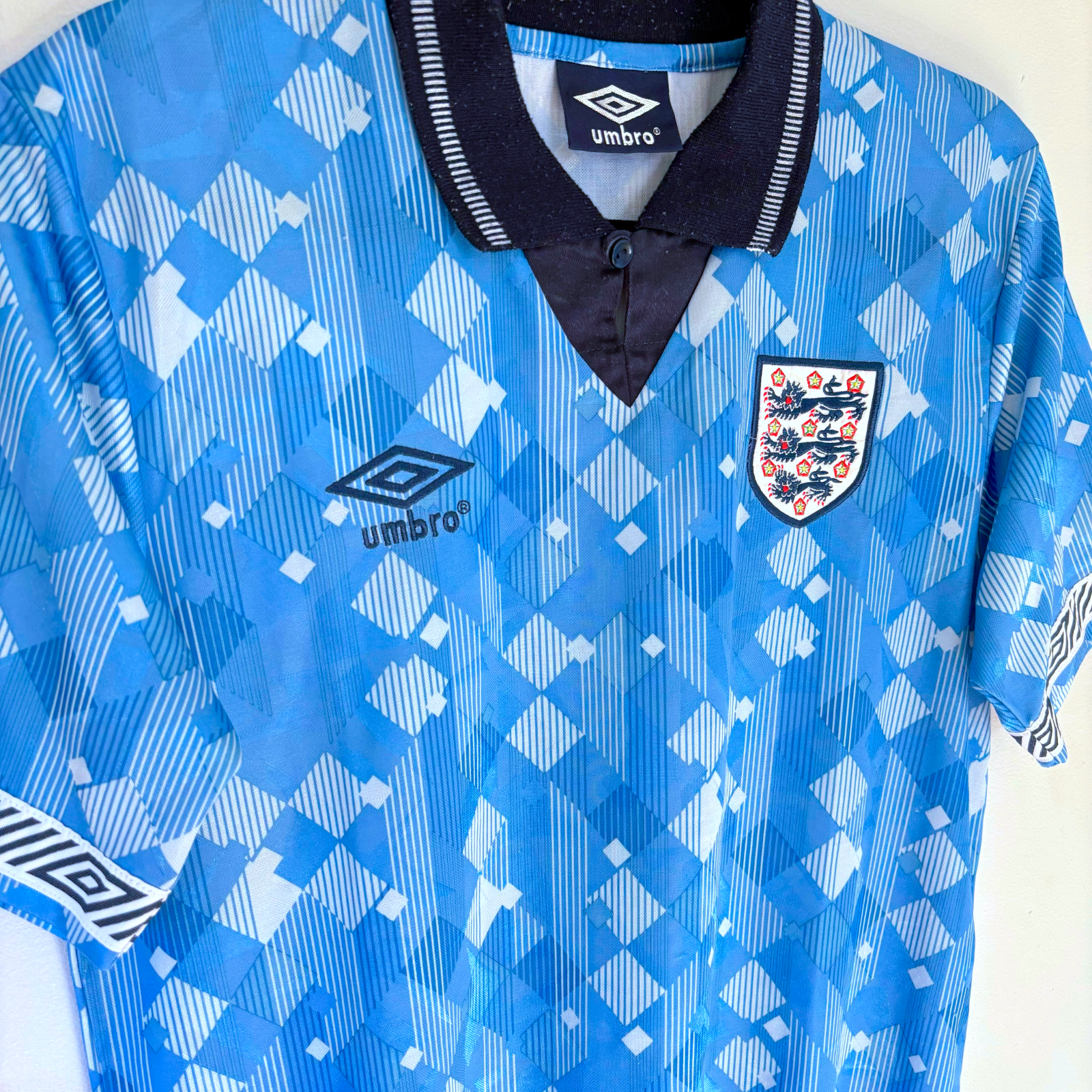 England 1990 blue vintage football shirt with Umbro logo and Three Lions crest, retro soccer jersey design. - England 1990/1991/1992 Third 3rd Blue Umbro Football Shirt Reissue