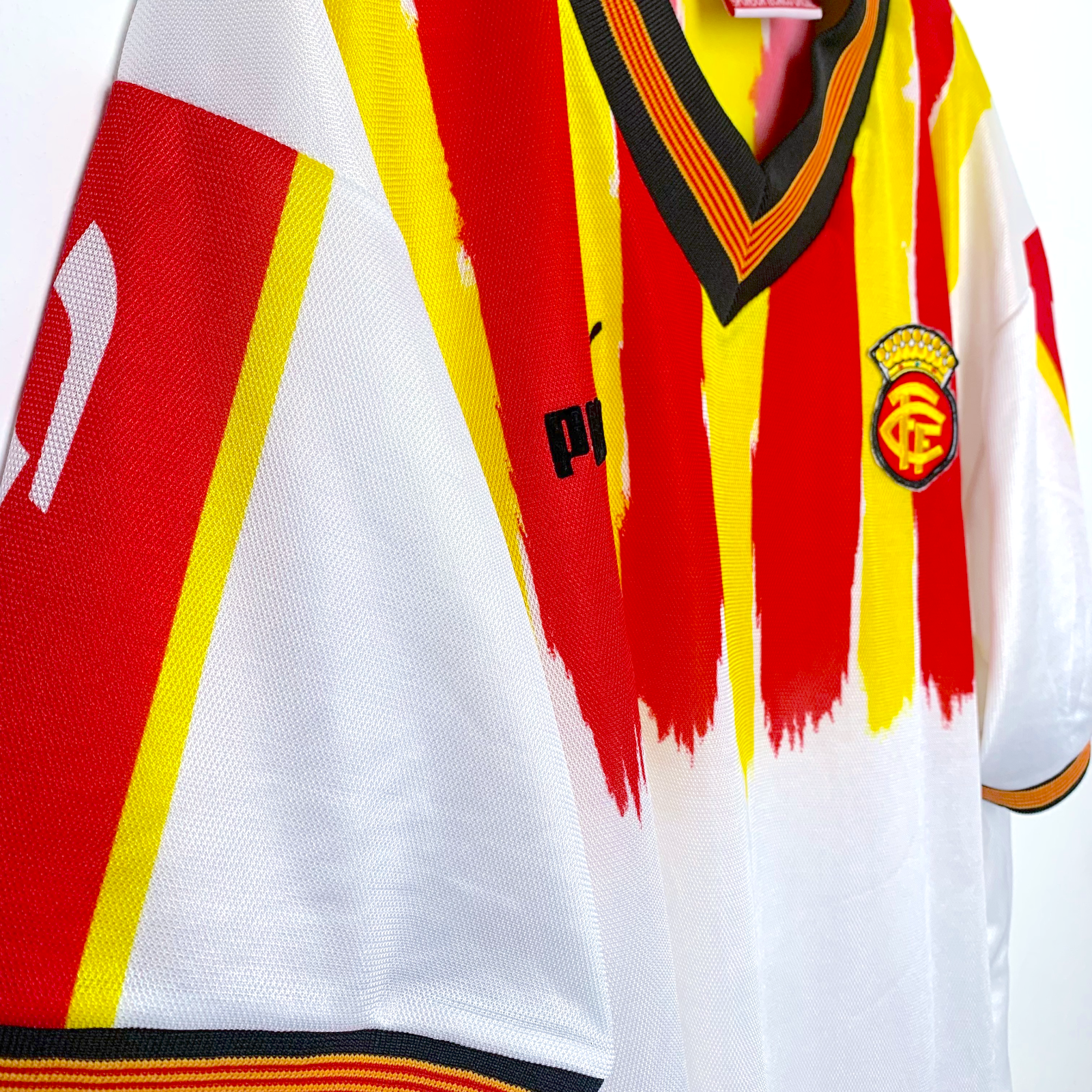 Side view of Catalunya old football shirt by Puma in white with red and yellow stripes on a white background