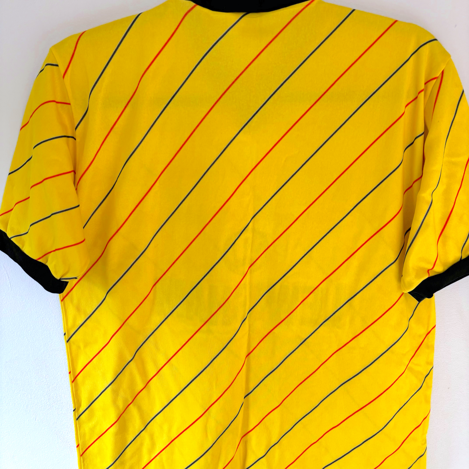 Yellow vintage football shirt with thin red and blue diagonal stripes and black collar and cuffs, retro soccer jersey style. - Millwall 1987/1988/1989 Away Football Shirt Spall