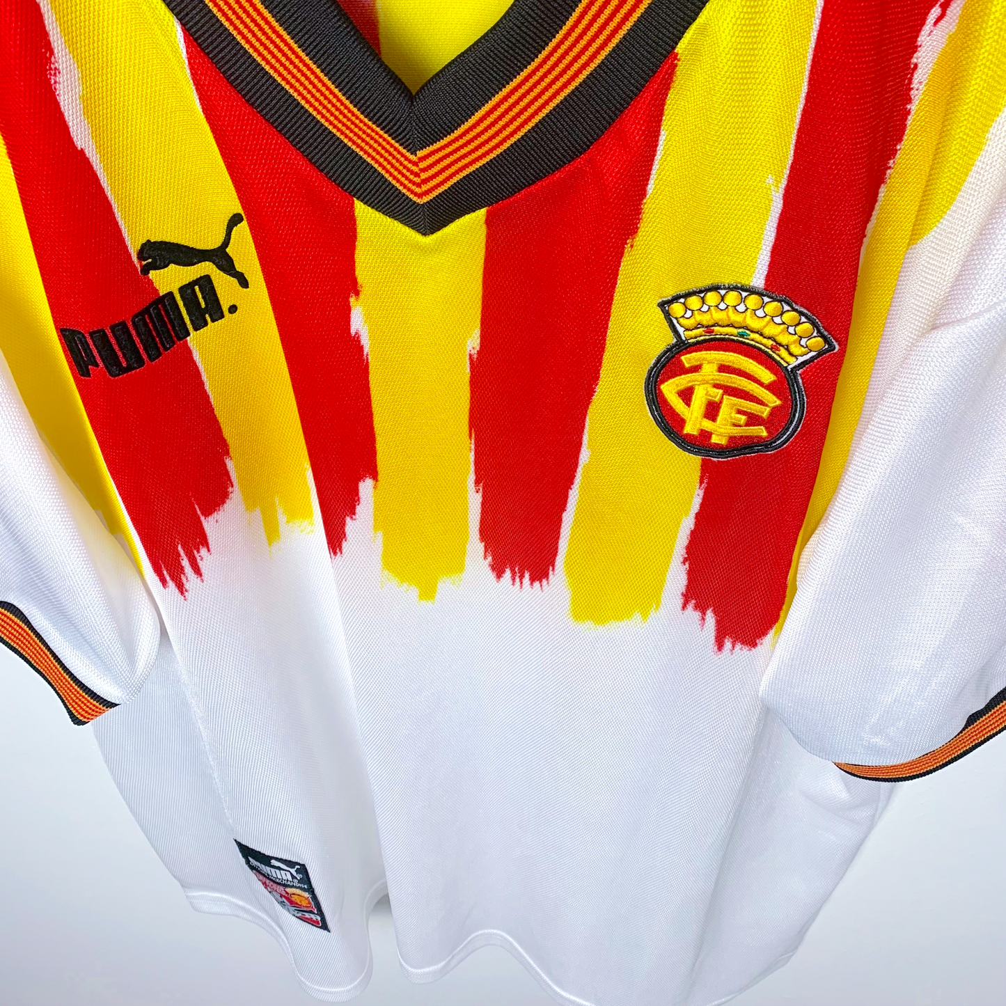 Close up downward view of Catalunya classic soccer jersey by Puma in white with red and yellow stripes on a white background