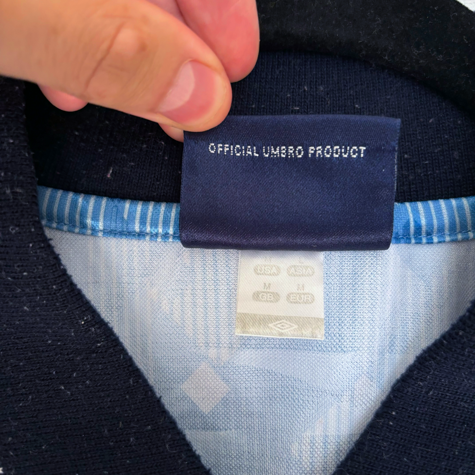 Close-up of official Umbro label on vintage retro football shirt collar showing navy tag and light blue trim detailing. - England 1990/1991/1992 Third 3rd Blue Umbro Football Shirt Reissue