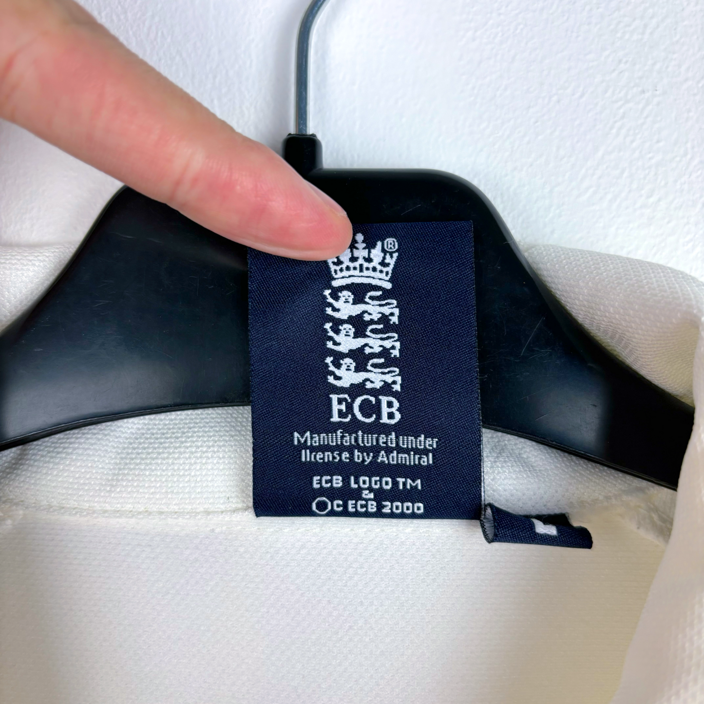 England 2005 vintage football shirt label showing ECB logo on white fabric with black hanger. - England 2005/2006/2007/2008 Ashes Cricket Shirt
