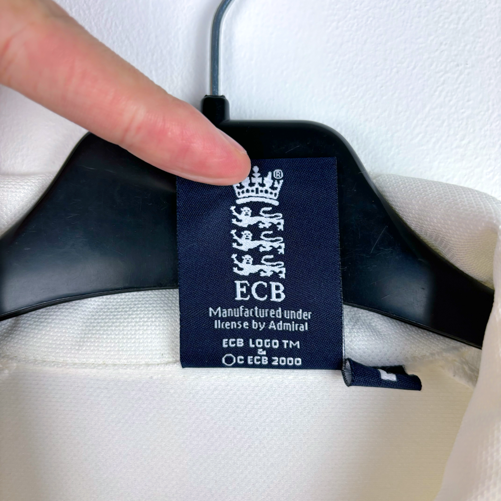 England 2005 vintage football shirt label showing ECB logo on white fabric with black hanger. - England 2005/2006/2007/2008 Ashes Cricket Shirt