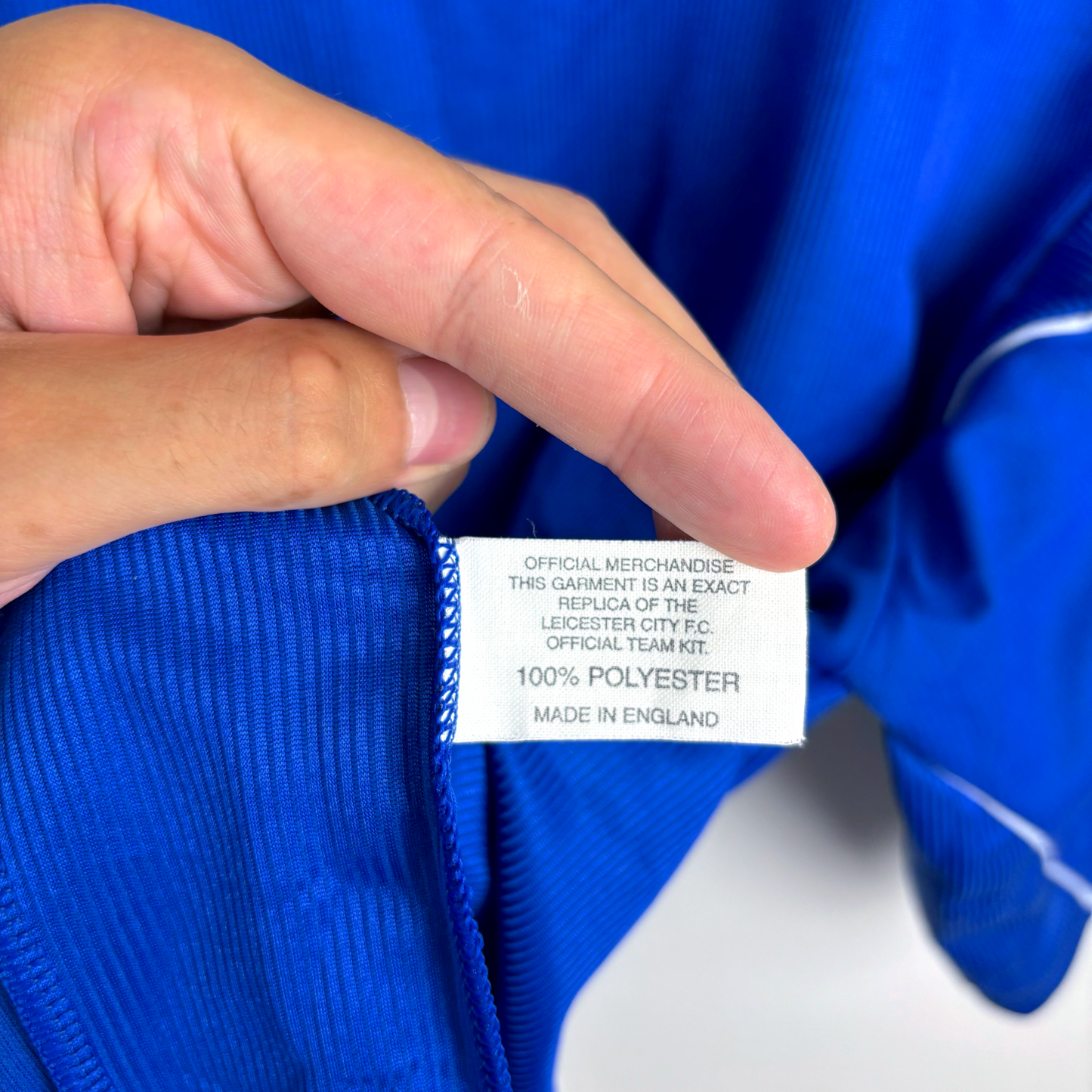 White fabric tag on blue vintage football shirt showing Le Coq Sportif official merchandise details. - MINT Leicester City 2000-2001 Home Football Shirt Le Coq Sportif