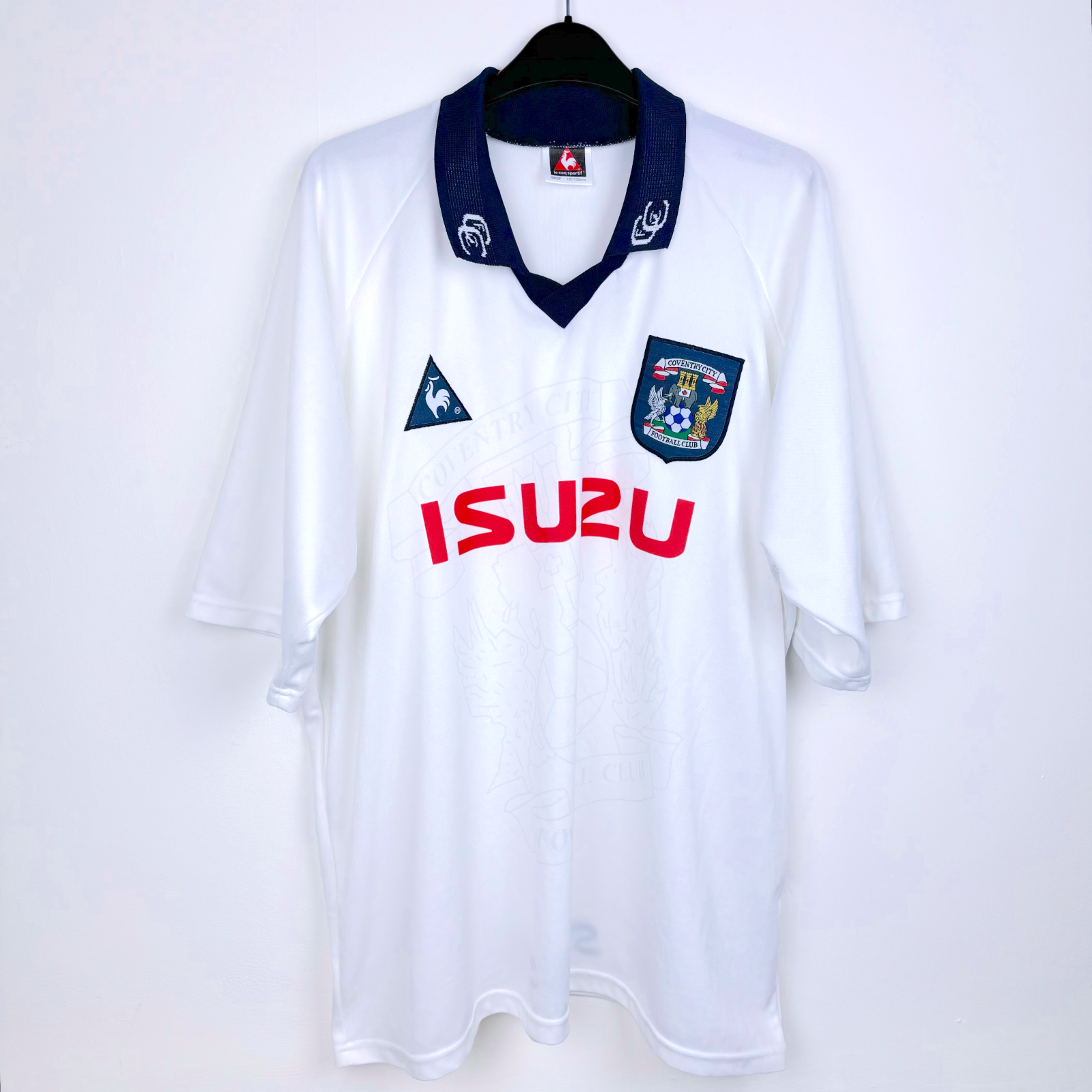 Frront view of white Coventry City vintage football shirt produced by le coq sportif. Embroidered Coventry badge with red Izuzu sponsor.