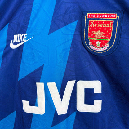 Close up of sponsor and badges on Arsenal 1995-1996 Nike away vintage soccer jersey. Two-tone navy and blue body with lightning bolt pattern. JVC sponsor.