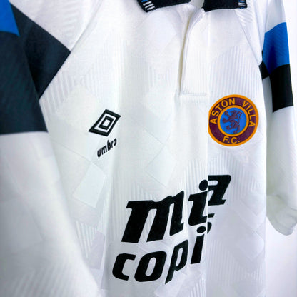 Side view of Aston Villa 1990-1993 away retro football shirt made by Umbro. Sublimated jacquard pattern ion white body. Black and blue trim with black Mita Copiers sponsor.