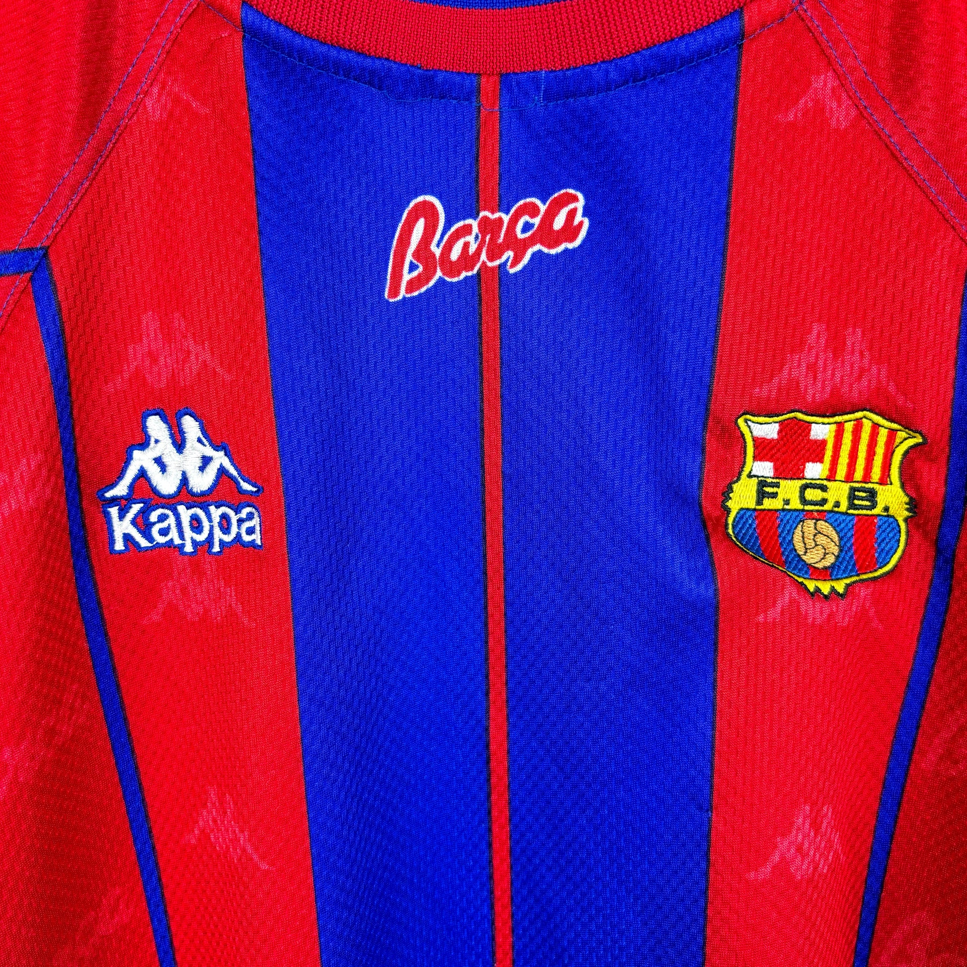 Badges close up on FC Barcelona 1997-1998 home vintage soccer jersey made by Kappa. Red and blue stripes with embroidered badge.