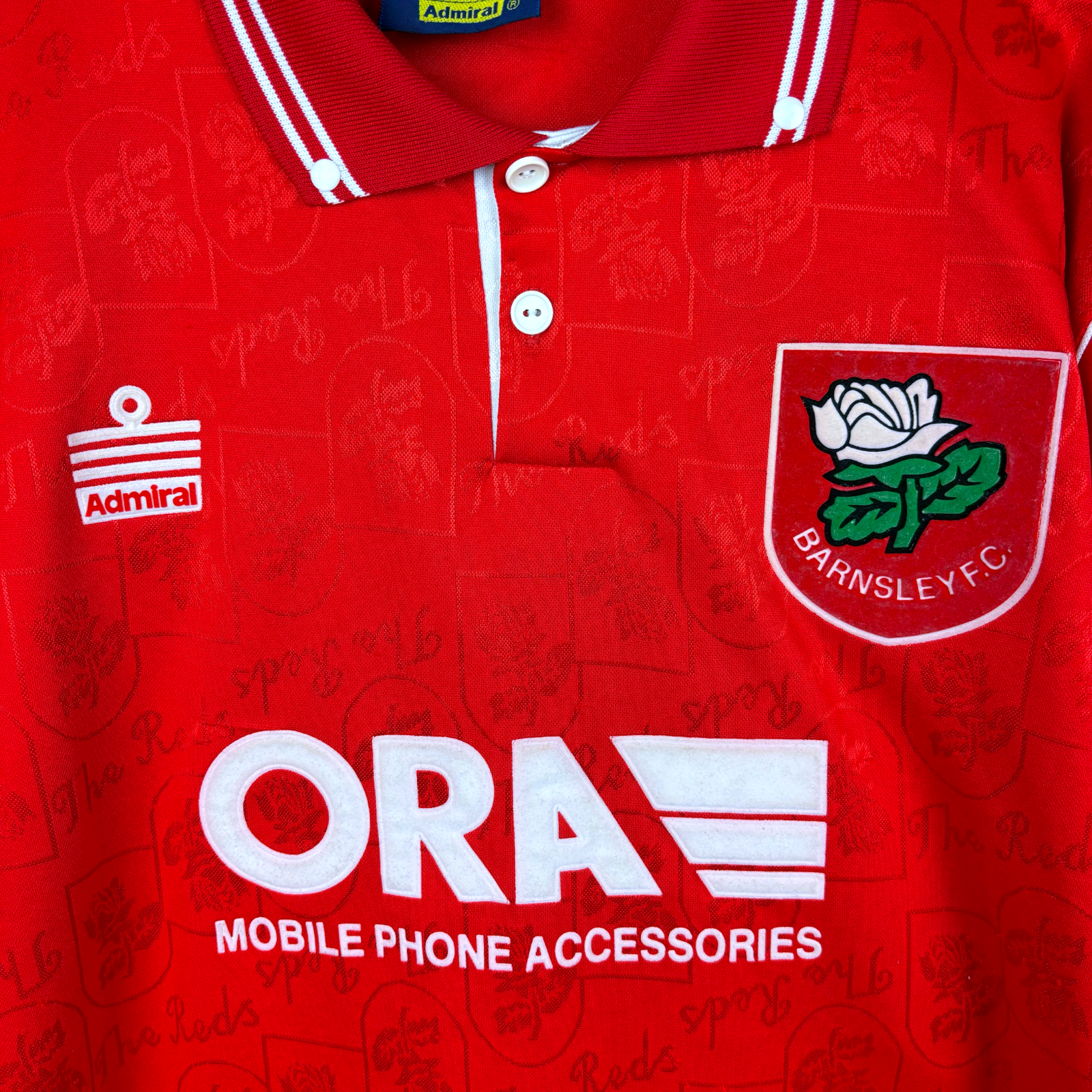 Barnsley 1996-1997 home classic football shirt produced by Admiral. Close up of ORA sponsor and Admiral logo as well as club badge.