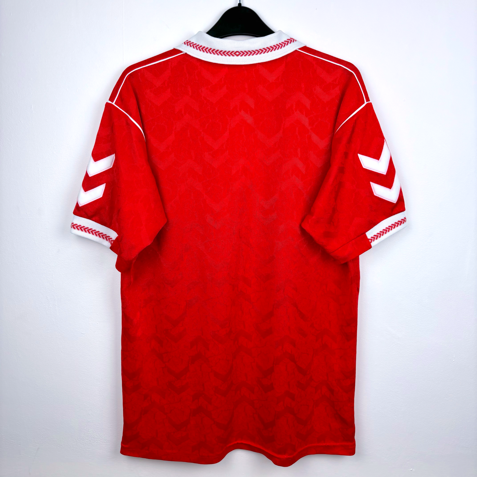 Rear view of old Benfica home soccer jersey 'hummel' and 'Casino Estoril' text, featuring Benfica club crest. Red body with white trim.