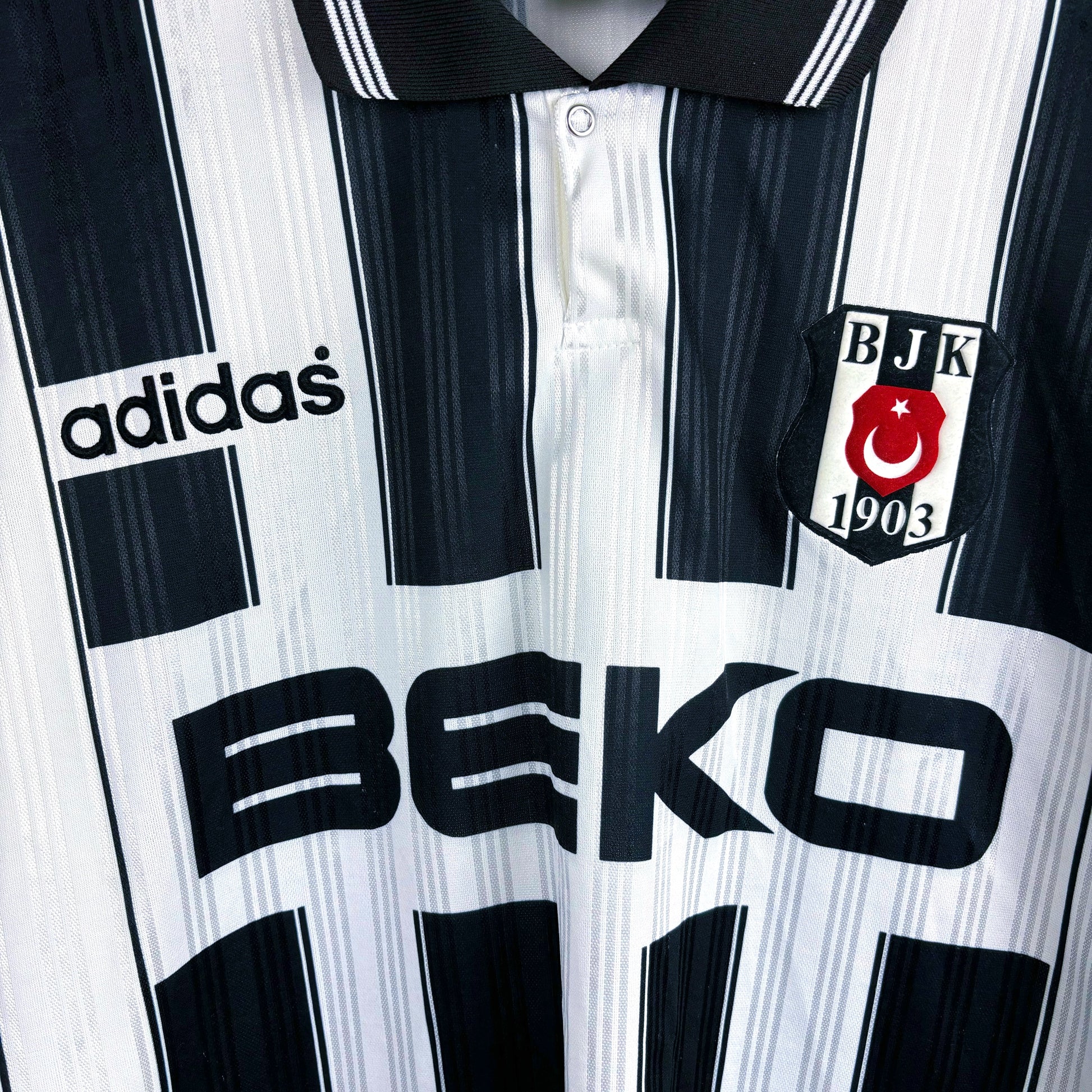 Close up of club badge and BEKO sponsor. Besiktas 1996-1997 away adidas retro soccer jersey with black and white stripes.