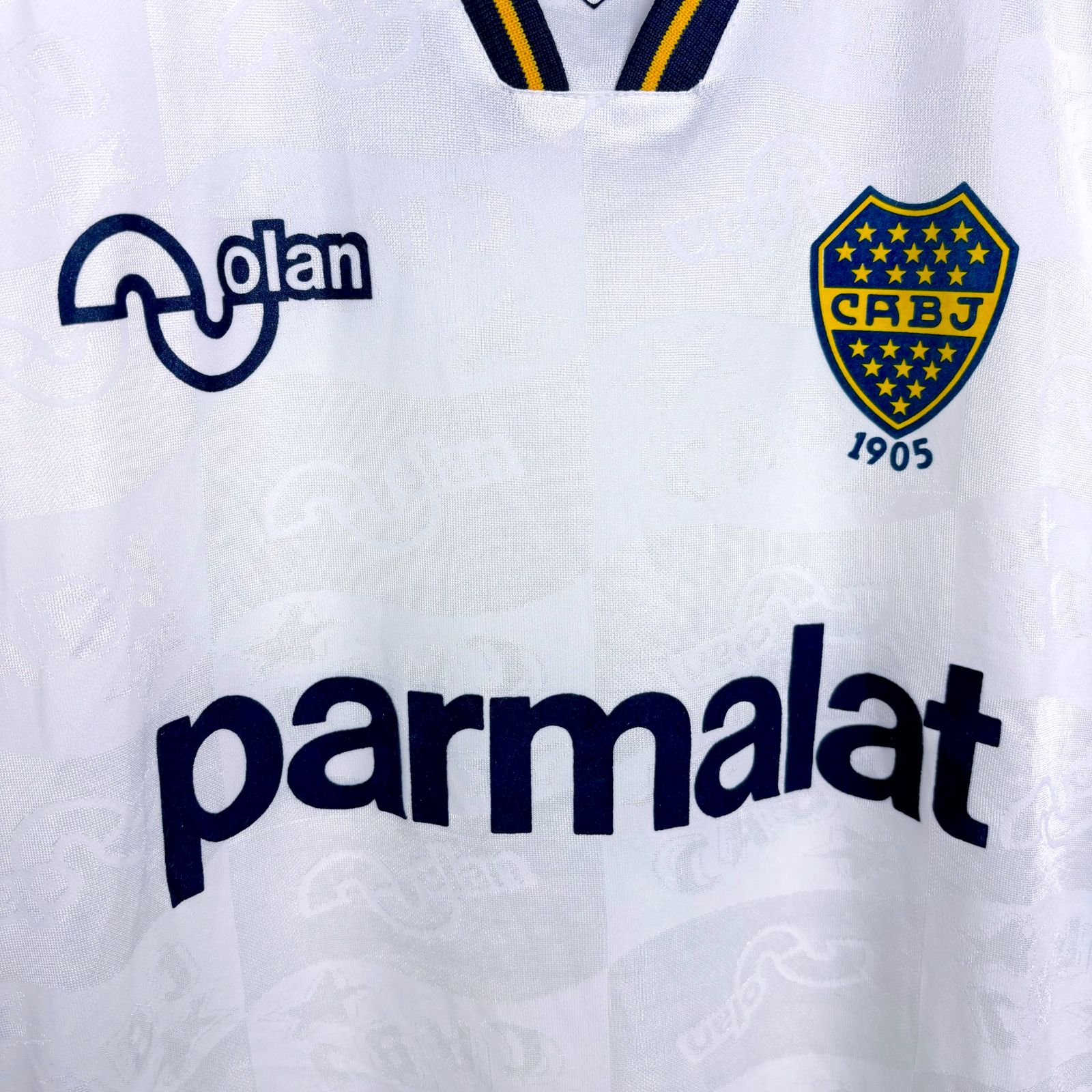 Boca Juniors 1995-1996 away classic football shirt produced by OLAN. Close up of Boca crest and OLAN and Parmalat sponsors in navy.