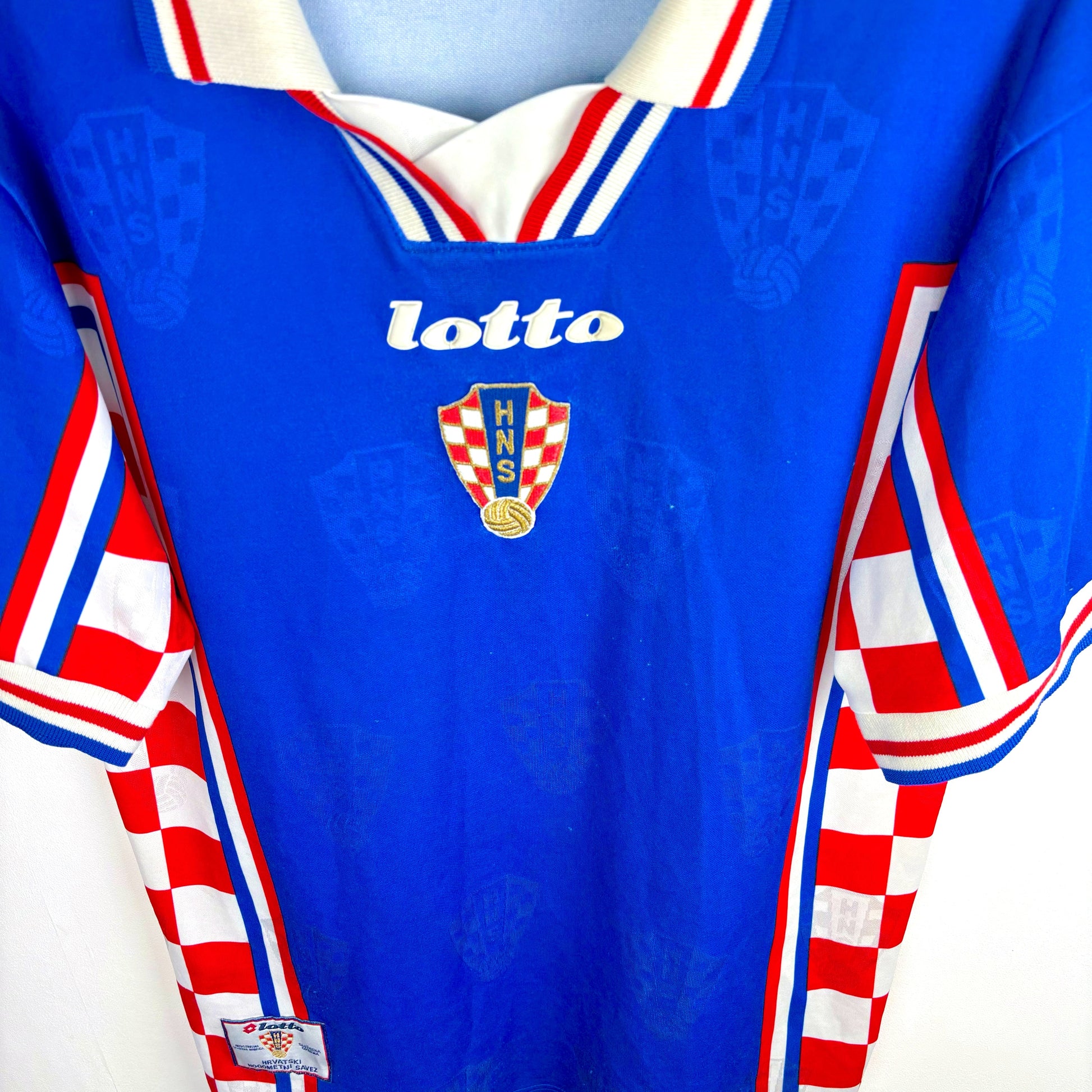 Downward view of Croatia 1998-2001 Lotto vintage football shirt. Blue body with checkered red and white panels.