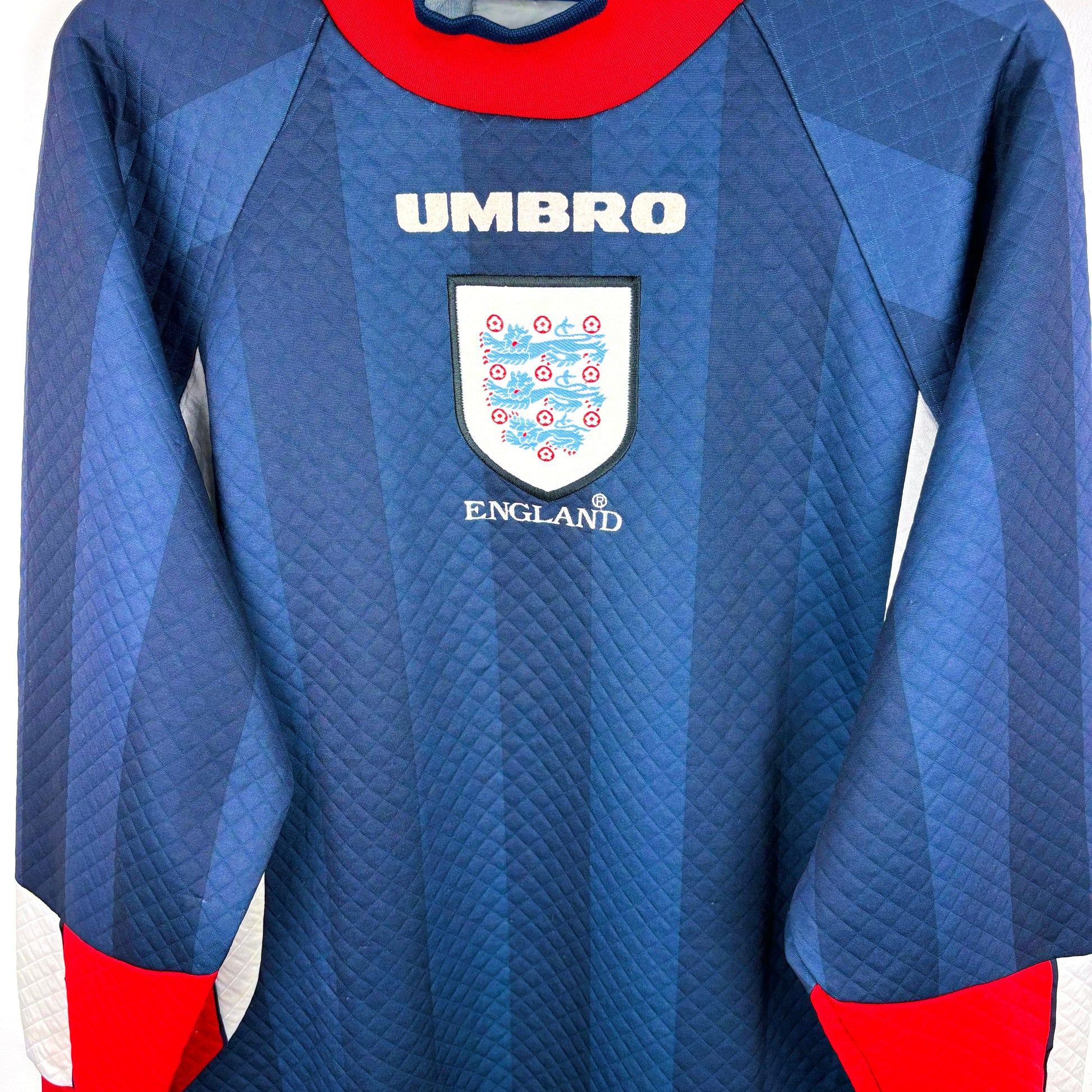 Side view of England 1997-1998 goalkeeper retro football shirt produced by Umbro. Dual navy body with red collar and tipped sleeves. Worn during 1998 World Cup.