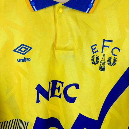 Close up view of Everton 1990-1992 away classic football shirt made by Umbro. Blue sublimated zig-zag across yellow body . NEC sponsor and old club crest.