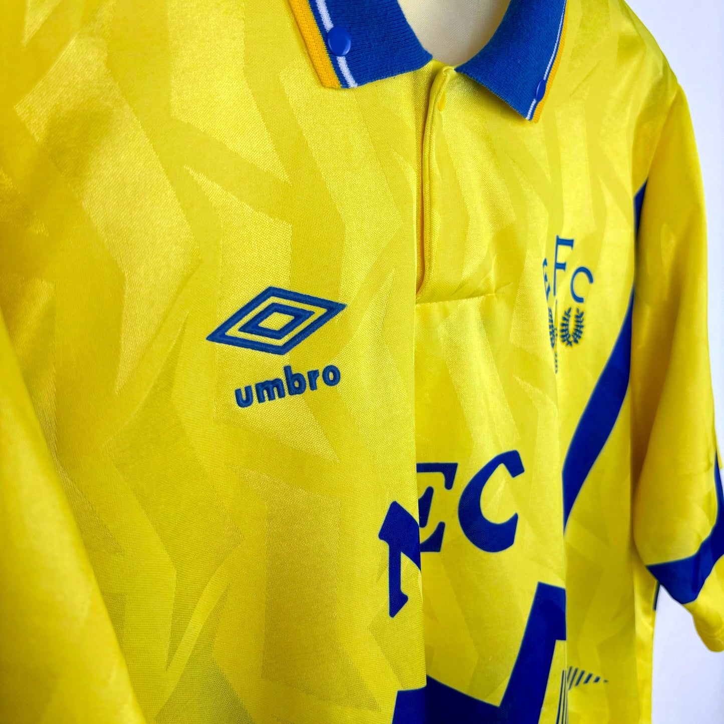 Side view of Everton 1990-1992 away retro football shirt made by Umbro. Blue sublimated zig-zag across yellow body . NEC sponsor.