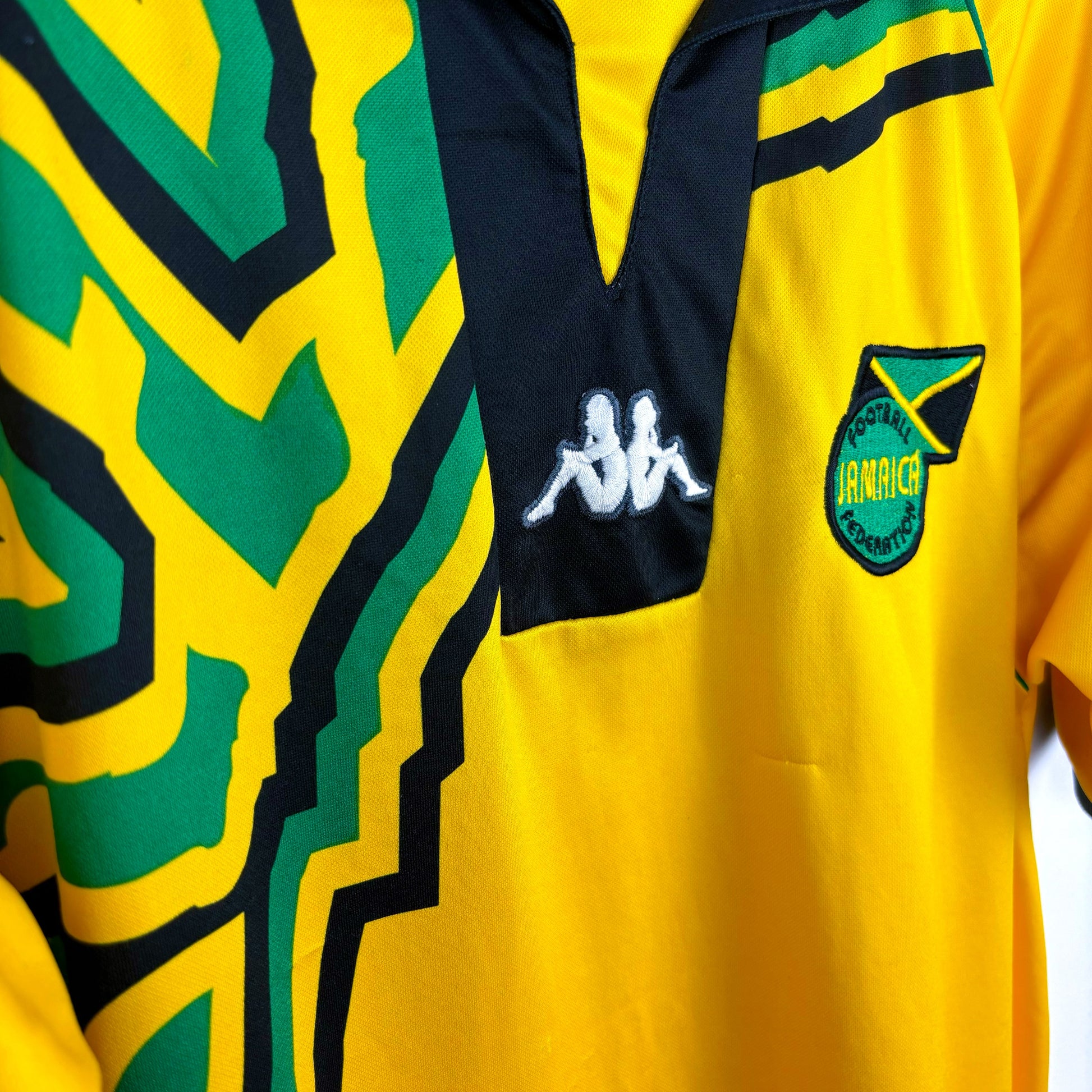 Side view of Jamaica 1998-1999 Kappa home retro soccer jersey. Yellow body with black and green trim.