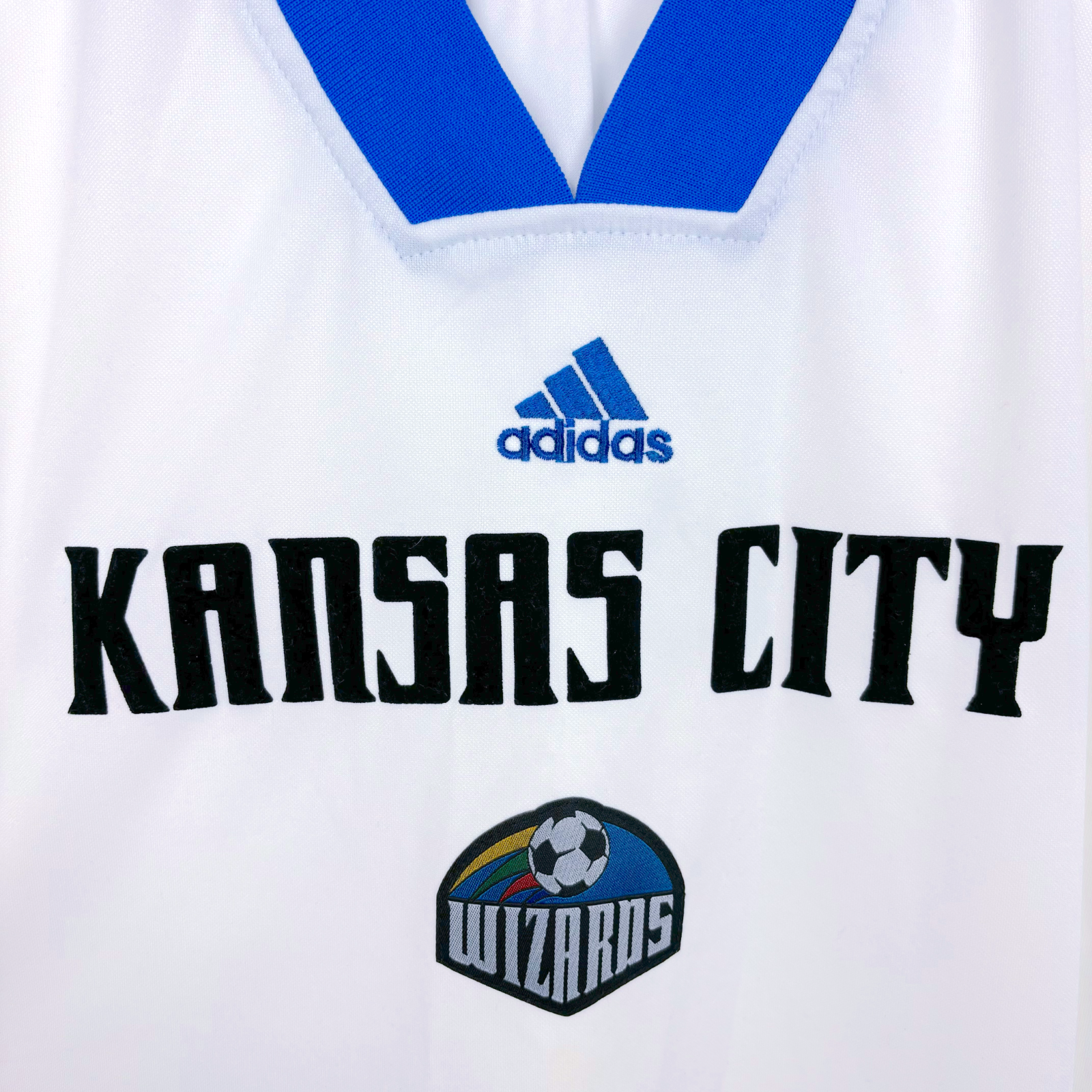 Close up Kansas City 1997-1998 classic soccer jersey produced by Adidas. Black 'Kansas City' text with adidas logo and club crest either side.