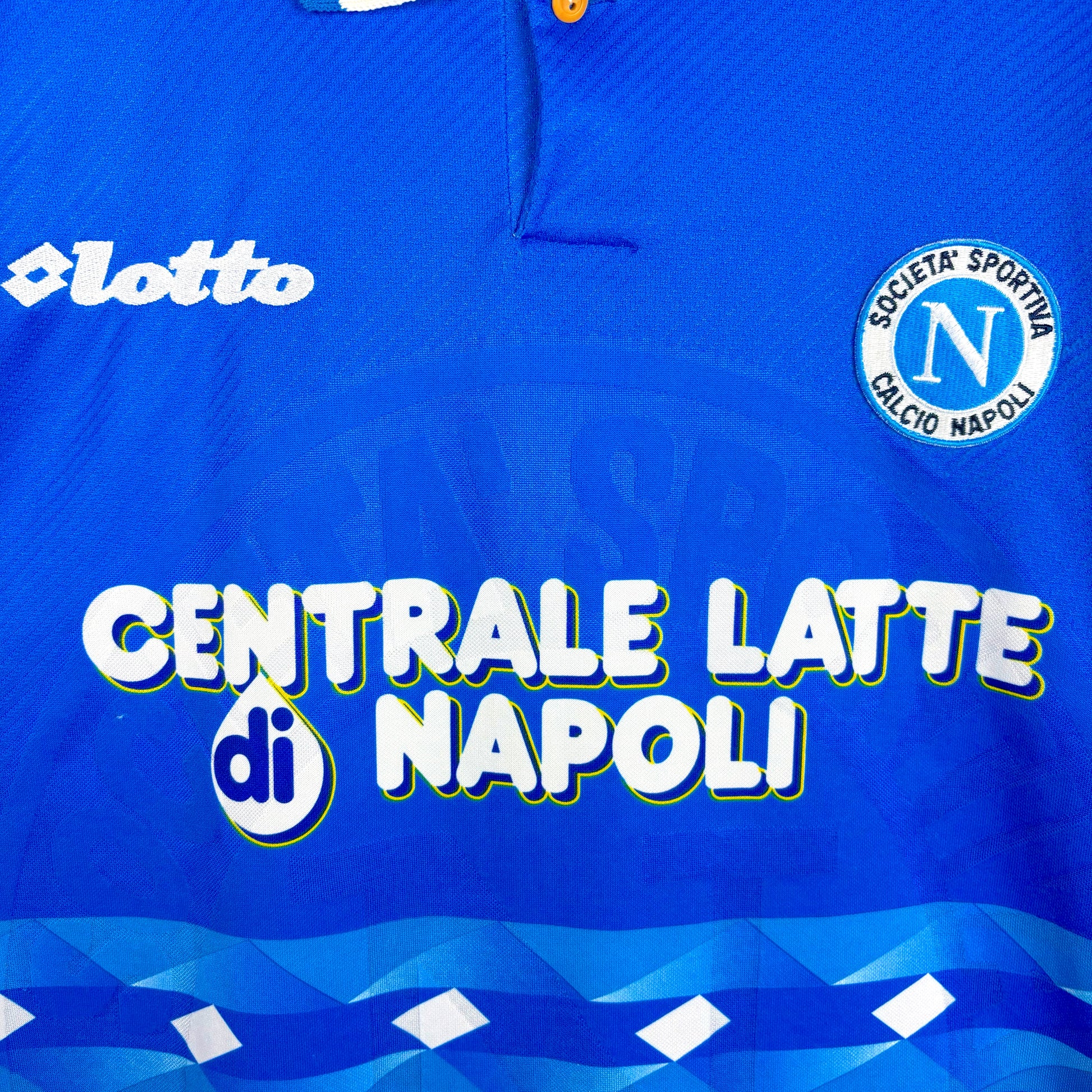 Close up of badges and sponsor on Napoli 1996-1997 Lotto home classic football jersey. Blue body with sublimated pattern. Centrale Latte di Napoli sponsor.