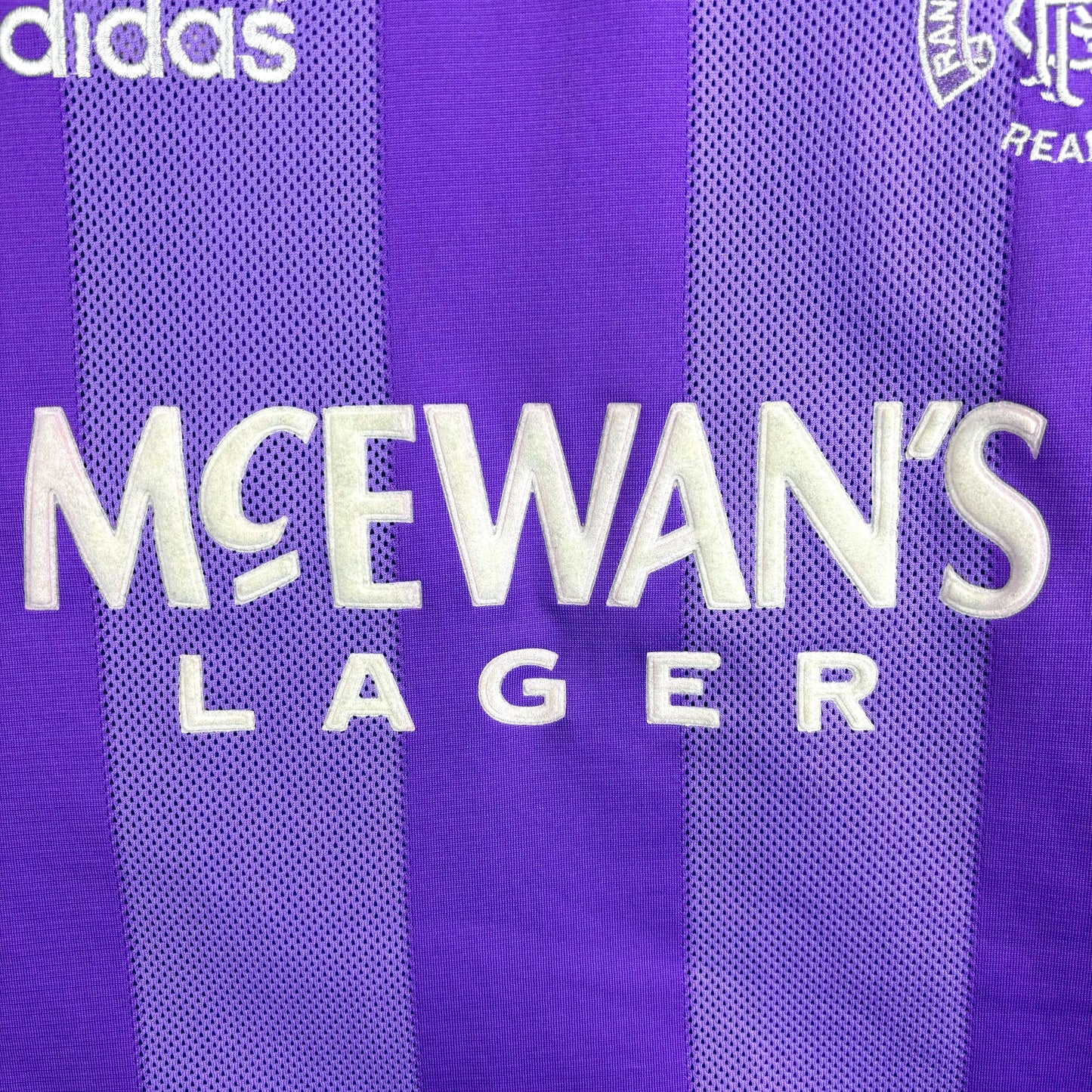 Close up of McEwan's Lager sponsor on Rangers 1994-1995 adidas European retro football shirt in lilac with black collar.