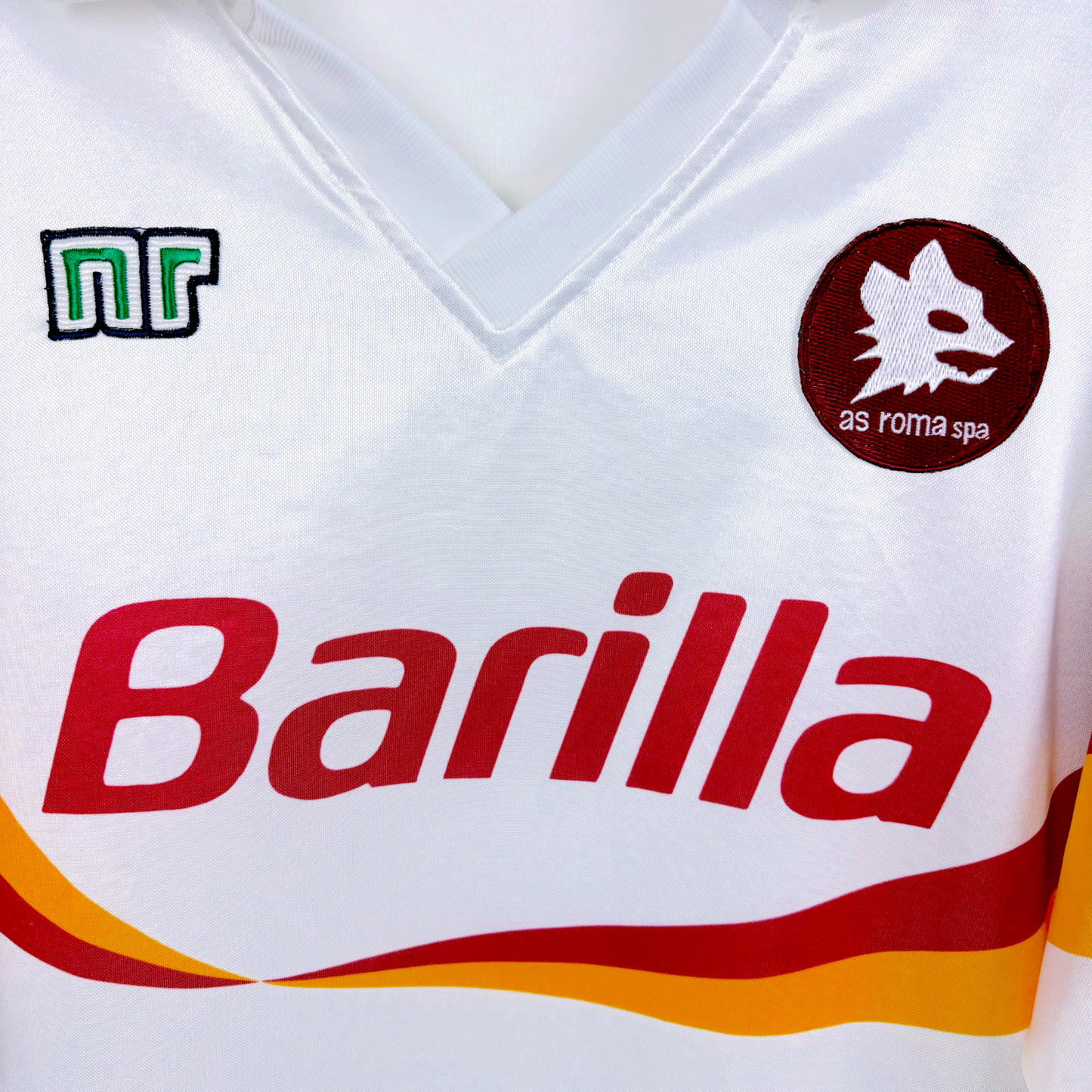 Roma classic football shirt produced by Ennerre. White body featuring orange and maroon swoosh across chest. Sublimated Barilla sponsor and embroidered Roma badge.