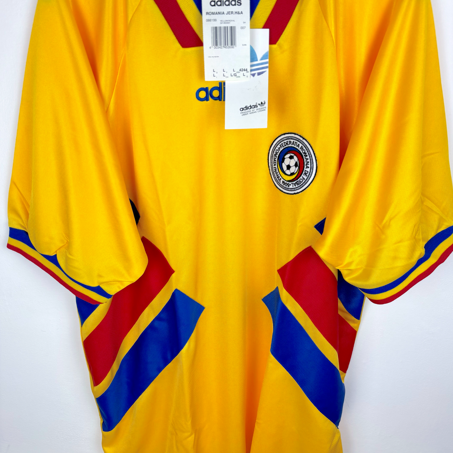 Romania 1994-1995 vintage football shirt produced by Adidas. Sideways view of yellow body and angled red and blue stripes.